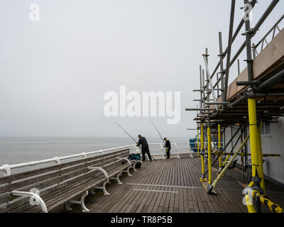 Cromer, Norfolk, Großbritannien. 19. Mai 2019. Vater und Sohn angeln im Meer aus dem fernen Ende der Pier, die von anderen Menschen, an einem nebligen Morgen Stockfoto