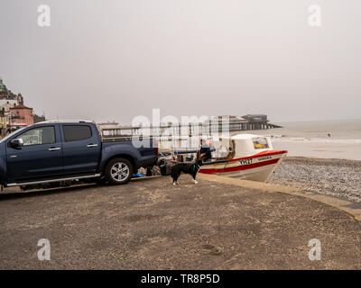 Cromer, Norfolk, Großbritannien. 19. Mai 2019. Ein Fischer auf seinem traditionellen crab Fischerboot mit seinem Hund auf dem Trockenen Stockfoto