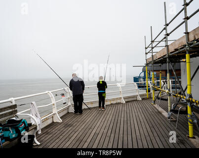 Cromer, Norfolk, Großbritannien. 19. Mai 2019. Vater und Sohn angeln im Meer aus dem fernen Ende der Pier, die von anderen Menschen, an einem nebligen Morgen Stockfoto