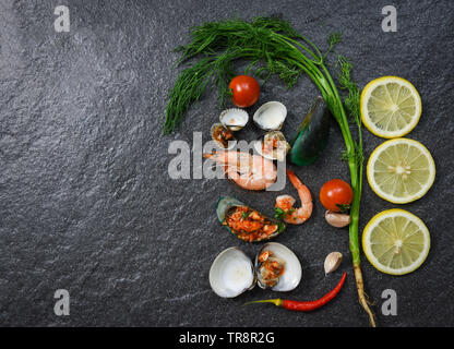 Seafood Platte mit Garnelen gekocht Gekochte Schalentiere Miesmuscheln herzmuscheln Zitronen Kräuter und Gewürze auf dunklem Hintergrund Stockfoto