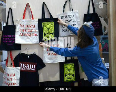 Verkäufer, die Tasche aus einem Ständer mit handgefertigten Taschen, Schriften über Sie anstößige Sprache enthalten. Messe "Knyzhkovyi Arsenal". 24. Mai 2019. Kiew, Ukraine Stockfoto