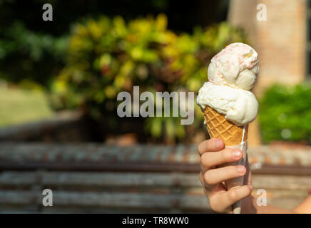 Junge asiatische Hand mit einem Tropfen Vanille Eiscreme Kegel Stockfoto