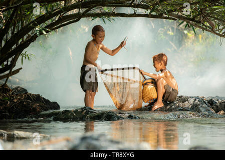 Asien Kinder froh Fischer auf dem Fluss stream/Der junge Freund gerne lustig Lachen fischen mit Netz und Fisch in der Hand an Landschaft leben kid Stockfoto