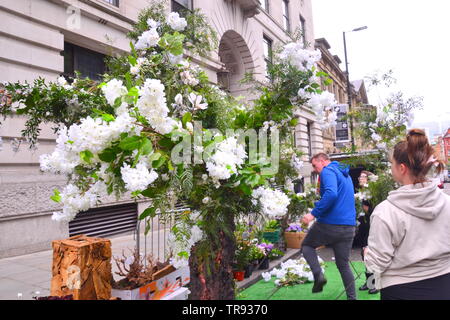 Der Manchester Flower Show, Teil der Manchester King Street Festival am 1.Juni - 2., 2019, bereitet zu öffnen. In diesem Jahr lautet das Thema: Flower Power! Menschen bauen ein Baum aus Blumen auf der Straße. Stockfoto