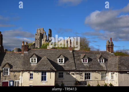 Die Ruinen von Corfe Castle thront auf einem Hügel hinter der Greyhound Pub. Stockfoto