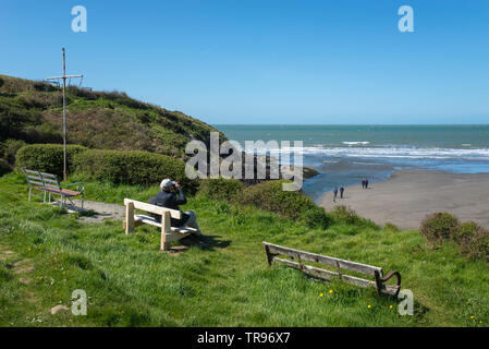 Paar genießt die Aussicht von Newport Sands in Pembrokeshire, Wales an einem sonnigen Frühlingstag. Mehr Menschen zu Fuß am Strand unten. Stockfoto