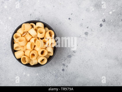 Bereit gesalzen Kartoffel Ringe, die als klassische Snack in schwarz Schüssel auf hellen Hintergrund. Ansicht von oben Stockfoto