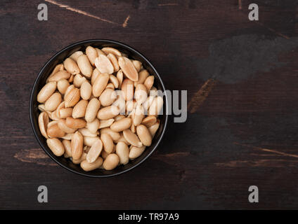 Gesalzen und geröstet Erdnüsse classic Snack in schwarz Schüssel auf Holz. Top View Stockfoto