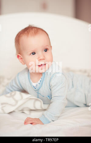 Smiling baby boy Aufwachen im Bett im Zimmer. Tragen Schlafanzug. Weg schauen. Guten Morgen. Stockfoto