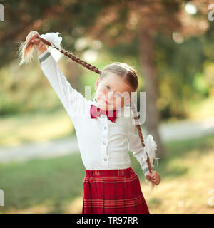 Lustige Schüler Mädchen tragen Schuluniform im Freien. Mit Blick auf die Kamera. Kindheit. Stockfoto