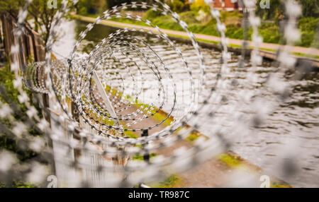 Auf der Suche durch den Stacheldraht auf einen Zaun in der Nähe der Grachten in Birmingham, England Stockfoto