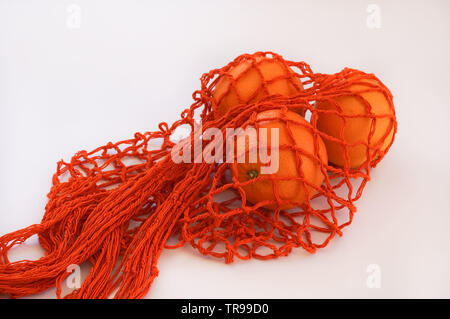 Handgemachte orange String Tasche mit drei Orangen weißer Hintergrund Stockfoto