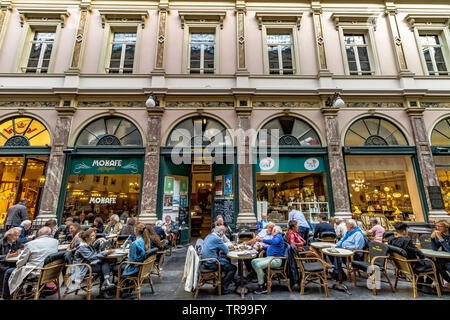 Die Menschen sitzen draußen Kaffee trinken Mokafe cafe in Les Galeries Royales Saint-Hubert, einem eleganten verglaste Einkaufspassage in Brüssel, Belgien Stockfoto