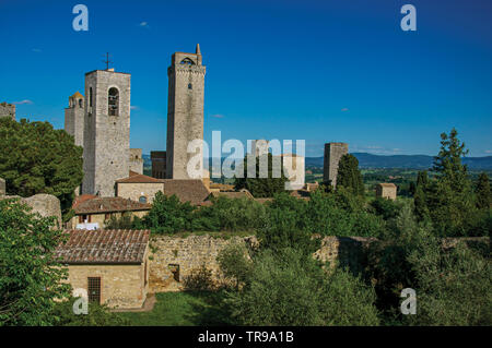 Aussicht auf die Dächer und Türme mit Bäumen und blauen sonnigen Himmel von San Gimignano. Eine tolle mittelalterliche Stadt berühmt für mehrere Türme in Italien. Stockfoto