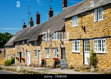 ABBOTSBURY, UK - Mai 22 Th, 2019: Das Dorf von Abbotsbury umfasst eine lange Straße mit Häusern aus Naturstein, von denen viele reetgedeckte sind, mit einigen dating von Stockfoto