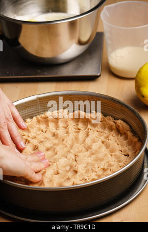 Zwei weiblichen kaukasischen Hände sogar die rohen Teig in einem schwarzen Backblech, backen Geschirr in den Hintergrund - Seitenansicht, Hochformat Stockfoto