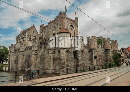 Brücke und Fahrrad vor der Burg Gravensteen an bewölkten Tag in Gent. Stadt mit intensiven kulturellen Lebens und gotischen Gebäuden in Belgien. Stockfoto