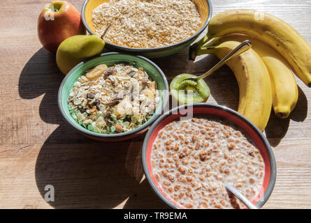 Kiwi, Banane, Birne, Apfel, Müsli in Schalen auf der hölzernen Hintergrund Stockfoto