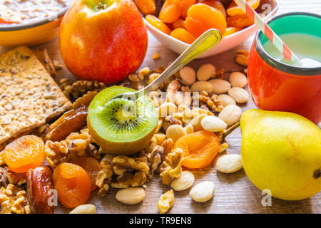 Gutes Frühstück - Obst, Getreide und Milch in Schalen auf einem hölzernen Tisch serviert Stockfoto