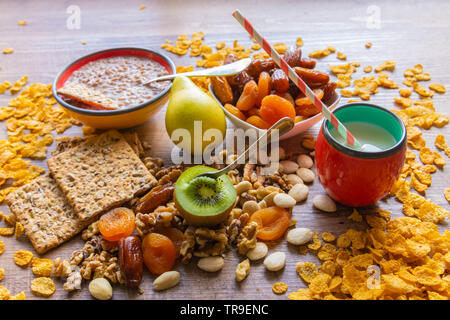 Schüssel mit Müsli und Milch, Früchte und getrocknete Pflaumen auf einem Holztisch - Frisch Frühstück zubereitet Stockfoto