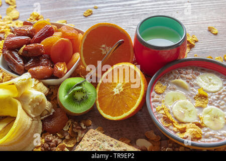 Gesundes Frühstück Schüssel, getrocknete Pflaumen, Datteln, Milch mit Müsli und Banane und Kiwi in den frühen Morgenstunden Stockfoto