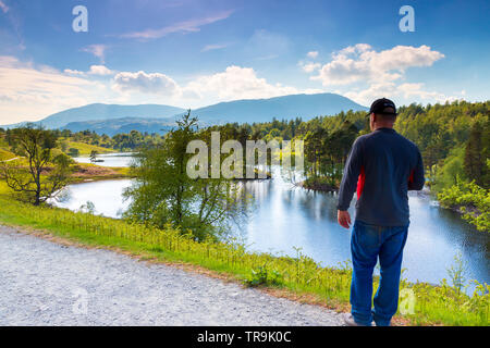 Menschen, die in die wunderschöne Aussicht von Tarn, wie im Nationalpark Lake District in Cumbria, Großbritannien an einem sonnigen Tag nach einem Tage Wanderung Stockfoto