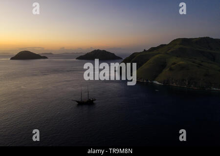 Aus der Vogelperspektive gesehen, ein kleines Schiff Kreuzfahrten unter den erstaunlichen und artenreichen Inseln Komodo National Park, Indonesia. Stockfoto