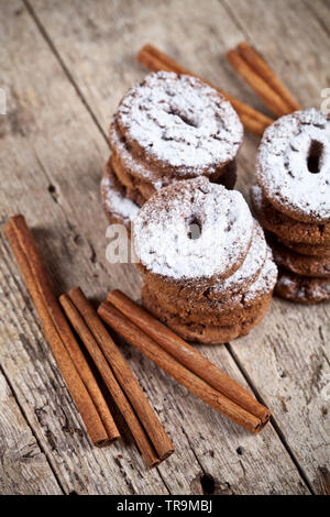 Frisch gebackenen Chocolate Chip Cookies mit Zucker Pulver und Zimtstangen auf hölzernen Tisch Hintergrund. Stockfoto