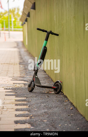 Elektrische kickbike vor einer grünen Wand gelehnt. Stockfoto