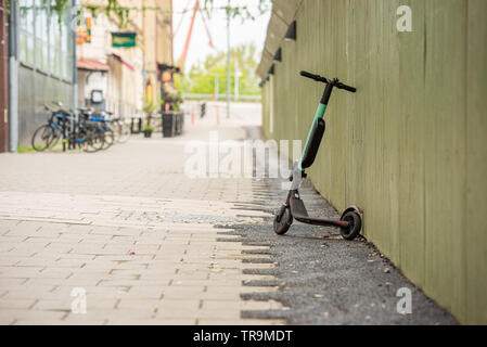 Elektrische kickbike vor einer grünen Wand gelehnt. Stockfoto