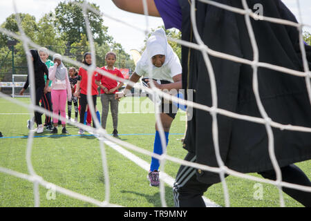 Ein muslimisches Mädchen mit Kopftuch schießt ein Fußball an Ziel während einer Trainingseinheit Stockfoto