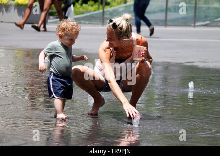 Philadelphia, PA, USA - 31. Mai 2019: Eine junge Mutter und ihr kleiner Sohn genießen Sie die Brunnen in Dilworth Park auf einen späten Frühling Tag. Stockfoto