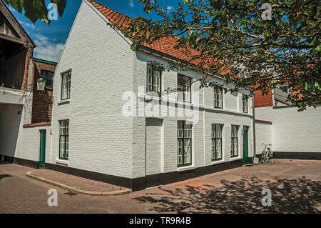 Fassade aus Ziegeln Häuser um Anmutigen kleinen Platz mit Blumen und Bäumen in Brügge. Charmante Stadt mit Grachten und alte Gebäude in Belgien. Stockfoto