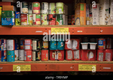 Dosen von Nahrungsmitteln, die auf Regalen in einer Nahrungsmittelbank in Wembley, London gespeichert Stockfoto