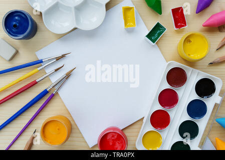 Konzept der Kunst: Zusammensetzung mit kleinen weißen Leinwand, umgeben von Pinsel, Farben und Palette auf einer hölzernen Hintergrund, mit Platz für Text Stockfoto