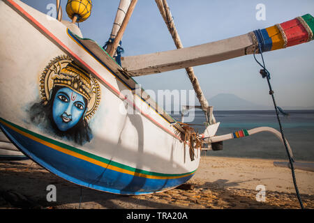 Indonesien Jukung oder traditionellen Fischerboot eingerichtet mit einem schönen Gemälde des hinduistischen Gottes Shiva und an einem Strand verankert in Nusa Penida Insel. Stockfoto