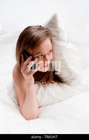 Frau im Bett am Telefon sprechen. Stockfoto