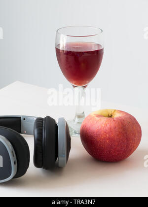 Wein Apple im Glas mit schwarzen hreadphone auf weißem Hintergrund, Stockfoto