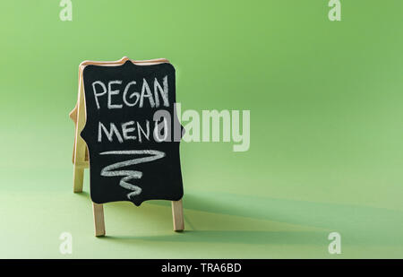 Tafel mit Text "pegan Menu' auf grünem Hintergrund mit Kopie Raum. Paleo plus vegan Konzept. Pegan Diät. Stockfoto