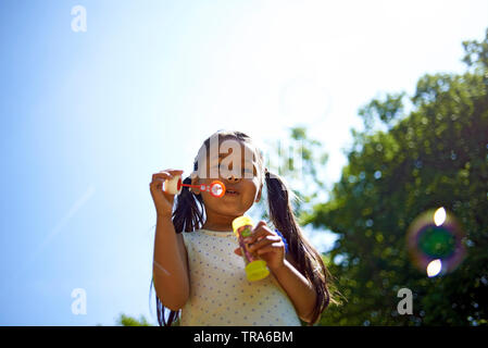 Nette junge asiatische Mädchen bläst Seifenblasen Spaß im Park im Sommer Sonnenschein Stockfoto