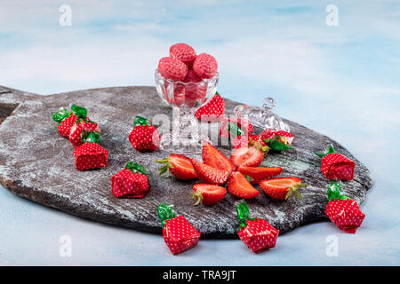 Erdbeere Süßigkeiten und Strawberry flavored candy Konzept mit Nahaufnahme auf süß und sauer Rot sauer Gürtel in Zucker isoliert auf einem hölzernen backgrou abgedeckt Stockfoto