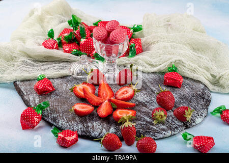 Erdbeere Süßigkeiten und Strawberry flavored candy Konzept mit Nahaufnahme auf süß und sauer Rot sauer Gürtel in Zucker isoliert auf einem hölzernen backgrou abgedeckt Stockfoto