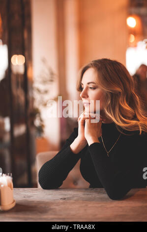 Schöne blonde Mädchen 22-24 Jahre alten im Cafe sitzen mit Blick auf das Fenster. Weg schauen. 20. Stockfoto