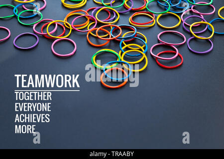 Teamwork Konzept. Gruppe von farbigen Gummiband auf schwarzen Hintergrund mit Wort Teamwork, Zusammen, jeder, erzielt und mehr Stockfoto