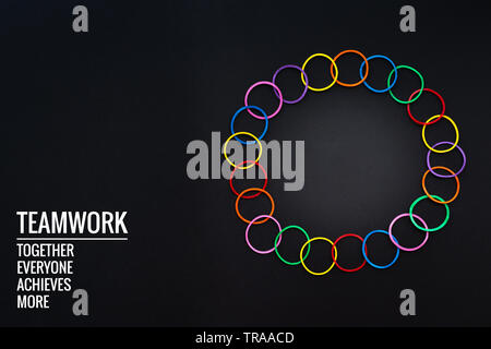 Teamwork Konzept. Gruppe von farbigen Gummiband auf schwarzen Hintergrund mit Wort Teamwork, Zusammen, jeder, erzielt und mehr Stockfoto