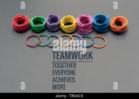 Teamwork Konzept. Gruppe von farbigen Gummiband auf schwarzen Hintergrund mit Wort Teamwork, Zusammen, jeder, erzielt und mehr Stockfoto