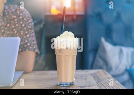 Eiskochkaffee auf Holztisch mit Arbeitsmann mit Laptop Stockfoto