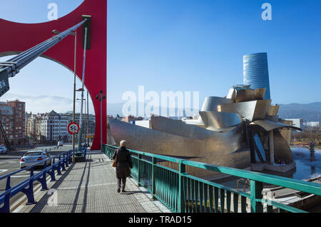 Bilbao, Vizcaya, Baskenland, Spanien: Eine Frau geht in Richtung Guggenheim Museum für Moderne und Zeitgenössische Kunst von dem Architekten Frank Gehry al konzipiert Stockfoto