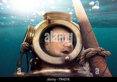 Porträt des Menschen in alten Taucheranzug und Helm unter Wasser. Lustige Taucher in retro Ausstattung mit Gesicht auf Glas zerquetscht. Stockfoto