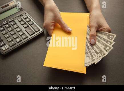 Konzept der empfangenden Gehalt in einem Kuvert mit. Gelber Umschlag mit Geld auf einem dunklen Tisch. Stockfoto